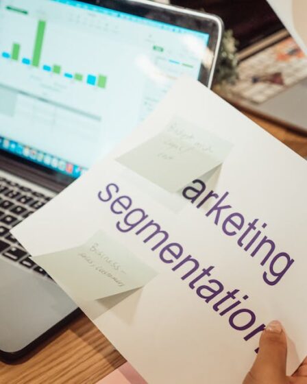 kobieta siedząca przed komputerem i trzymająca w ręce kartę z napisem "marketing segmentation"