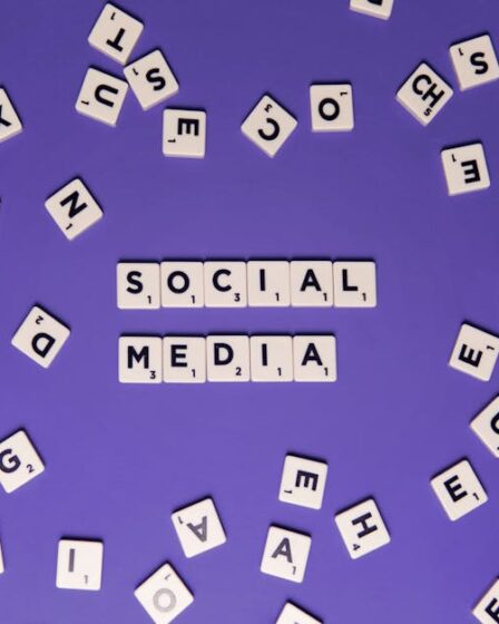 Rozrzucone klocki scrabble z literami układające się w napis SOCIAL MEDIA na fioletowym tle.