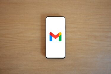 Smartfon z otwartą aplikacją Gmail leżący na drewnianym blacie.