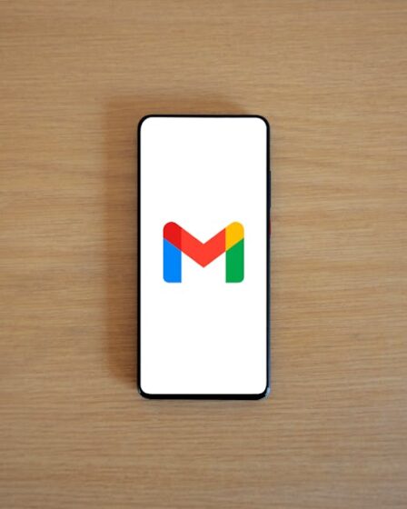 Smartfon z otwartą aplikacją Gmail leżący na drewnianym blacie.