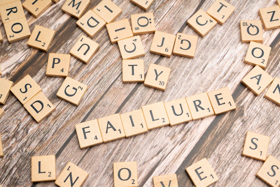 Litery ze gry Scrabble ułożone w słowo „FAILURE” na drewnianym stole.