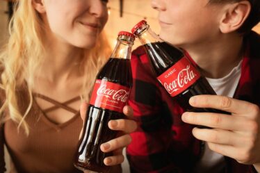 kobieta i mężczyzna stukający się butelkami coca-coli