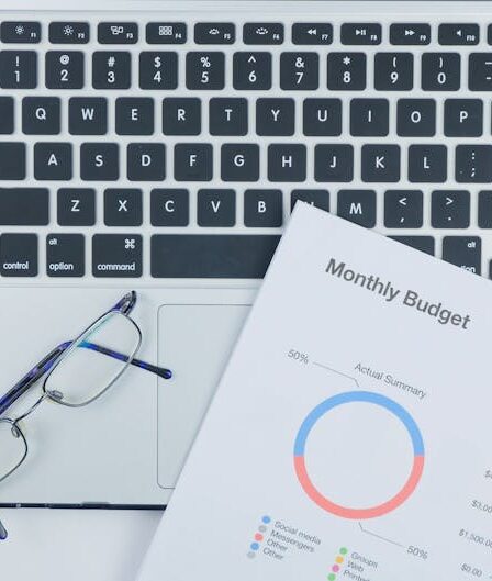 Laptop, okulary, kolorowe długopisy i dokumenty finansowe