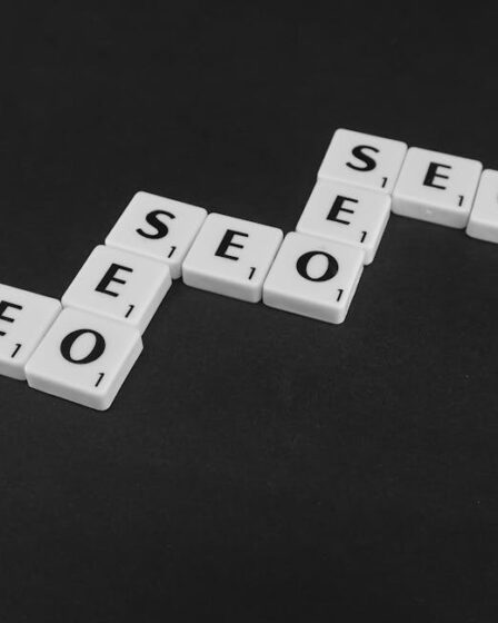 Białe płytki z literami ułożone w schodkowy napis SEO na czarnym tle.