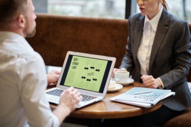 Mężczyzna i kobieta w biurowych strojach omawiają strategię SEO na laptopie.
