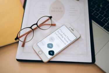 smartfon i skoroszyt ze strategią marketingową na klawiaturze laptopa