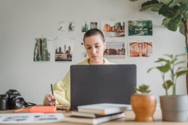 Osoba z krótkimi włosami pracuje przy laptopie z rysikiem w dłoni.