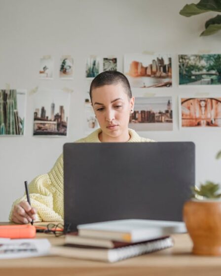 Osoba z krótkimi włosami pracuje przy laptopie z rysikiem w dłoni.