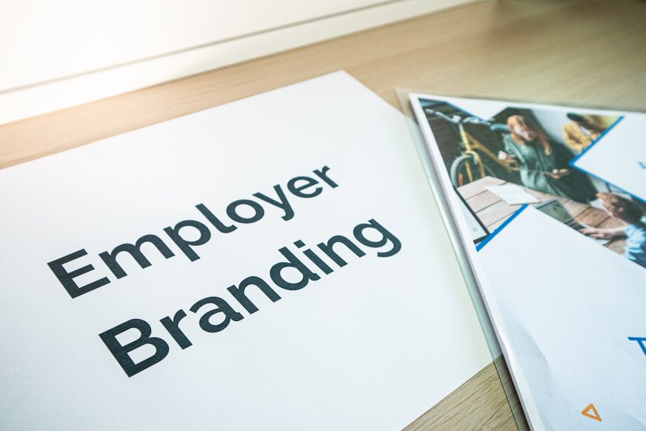 Kartka papieru z napisem Employer Branding leżąca obok wydrukowanych materiałów biznesowych.