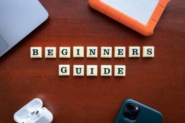 Białe klocki z literami układają się w napis Beginners Guide na drewnianym stole.