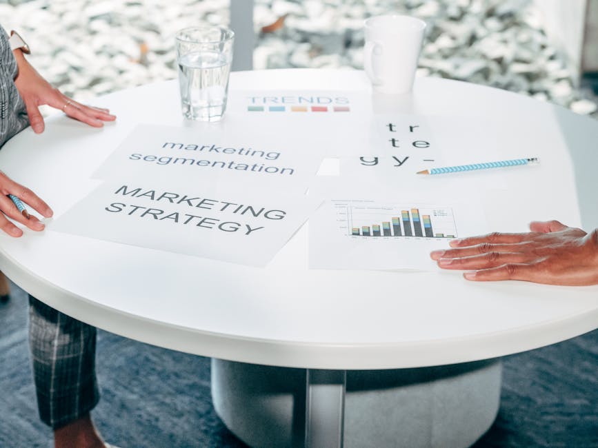 Osoby omawiające dokumenty dotyczące marketingu przy okrągłym białym stole w biurze.