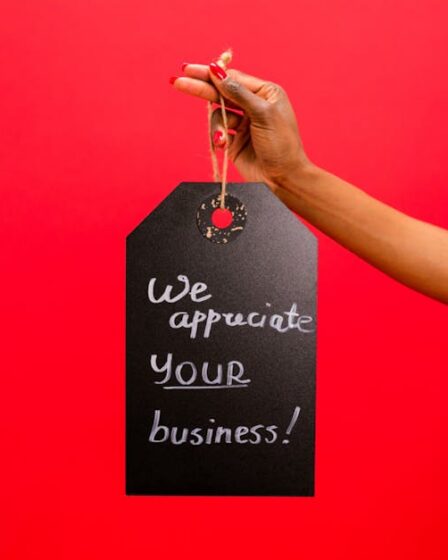 Ręka trzymająca zawieszkę z napisem "We appreciate your business" na czerwonym tle