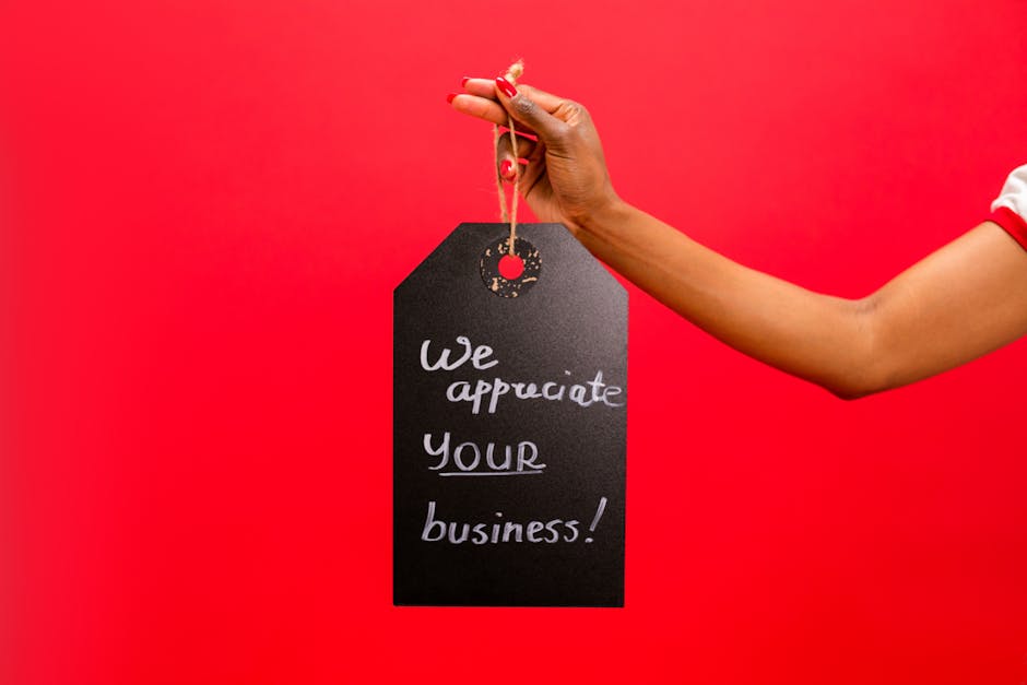 Ręka trzymająca zawieszkę z napisem "We appreciate your business" na czerwonym tle