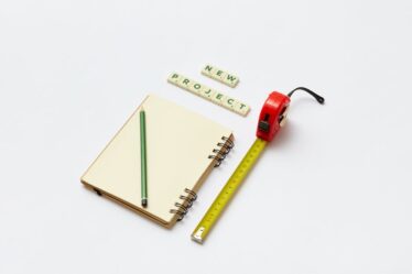 notes z ołówkiem, miarka i klocki scrabble układające się w napis "new project"