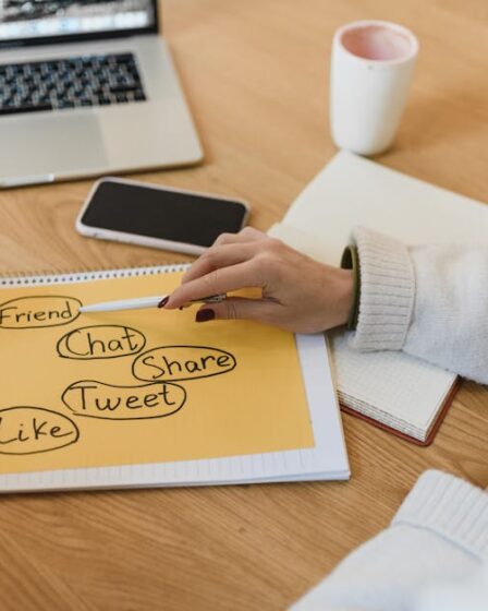 Dwie osoby planują strategię social media, zaznaczając na kartce hasła: friend, chat, share, tweet, like.