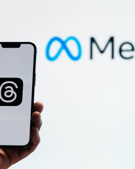 Dłoń trzymająca smartfon z logo aplikacji Threads na tle napisu Meta.