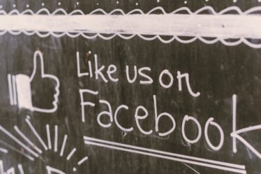 napis "Like us on Facebook" na czarnej tablicy