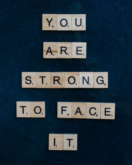 Napis „YOU ARE STRONG TO FACE IT” ułożony z drewnianych klocków do gry Scrabble.