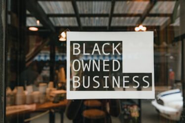 Naklejka z napisem „Black Owned Business” na szybie witryny sklepowej.