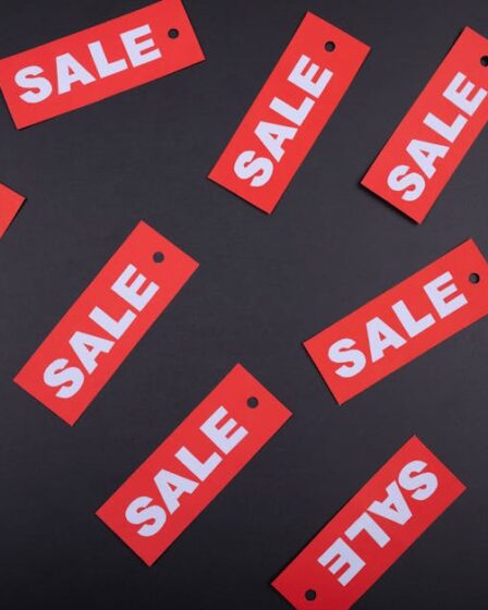 Czerwone metki z napisem SALE porozrzucane na ciemnym, szarym tle.