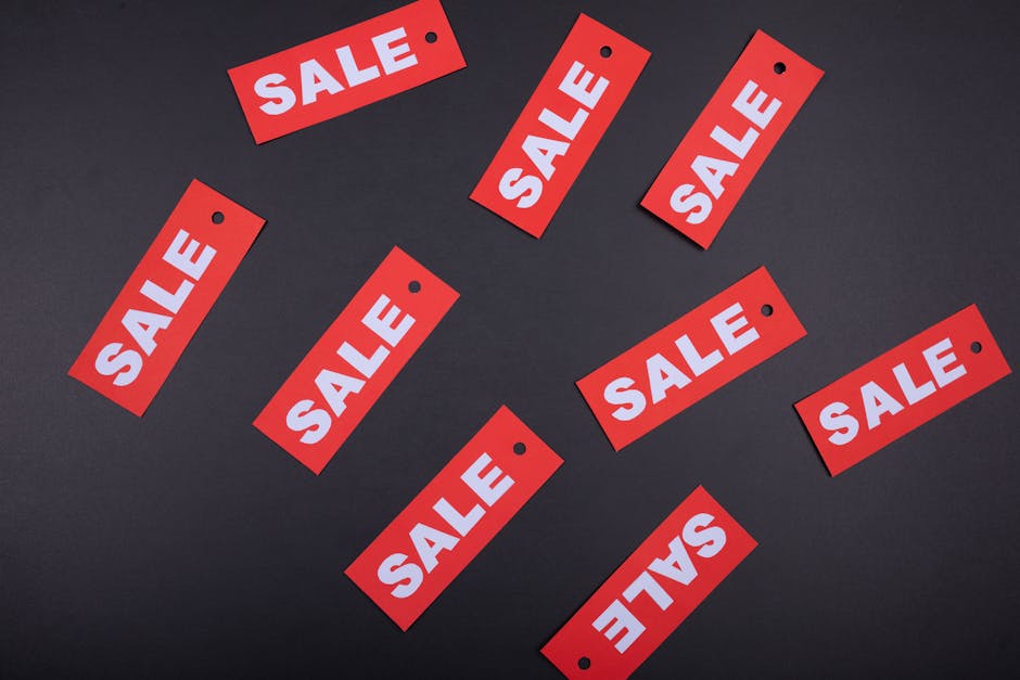 Czerwone metki z napisem SALE porozrzucane na ciemnym, szarym tle.